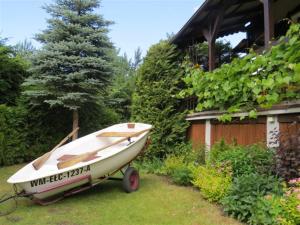 małą łódź siedzącą na przyczepie na podwórku w obiekcie Cudodomek na Mazurach w Woszczelach koło Ełku w mieście Ełk