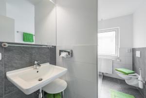 a white bathroom with a sink and a toilet at City Rooms Wels - contactless check-in in Wels