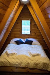 a bed in a wooden cabin with a window at Lodges Zacisze I in Giżycko