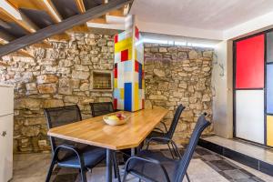 a dining room with a wooden table and chairs and a stone wall at House Mondrian in Vodnjan