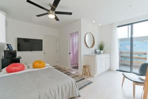 a white bedroom with a bed and a flat screen tv at Steps to the Beach, Rooftop Deck in San Diego