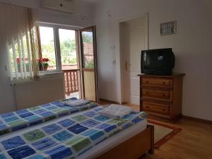 a bedroom with a bed and a tv on a dresser at Pensiunea Lőrincz *** Panzió in Sovata