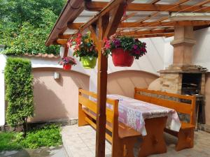 a table under a wooden pergola with potted plants at Pensiunea Lőrincz *** Panzió in Sovata
