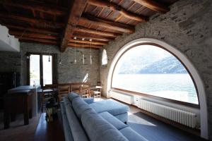 ein Wohnzimmer mit einem Bogenfenster und einem Sofa in der Unterkunft House on the lake shore of Laglio in Laglio