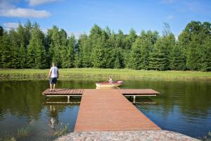 a man standing on a dock with a boat on a lake at Lodges Zacisze I in Giżycko