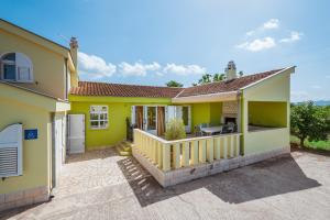 ein gelbes Haus mit einer Veranda und einem Balkon in der Unterkunft Villa Usce in Komin