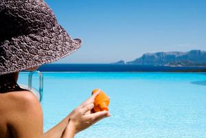 une femme dans un chapeau tenant un objet orange près de l'eau dans l'établissement Hotel Luna Lughente, à Olbia
