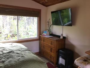 a bedroom with a bed and a flat screen tv at Volcano Eco Cabin & Eco Lodge in Volcano