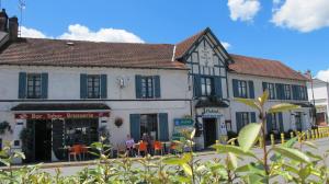 Un bâtiment avec des personnes assises à l'extérieur dans l'établissement Hôtel Au Bord du Monde, à Neuvy-sur-Barangeon