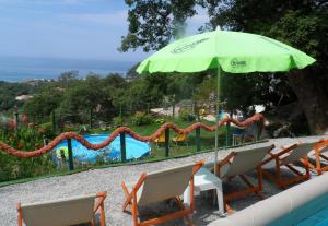 a green umbrella and chairs next to a swimming pool at Pataki Guesthouse in Petrovac na Moru