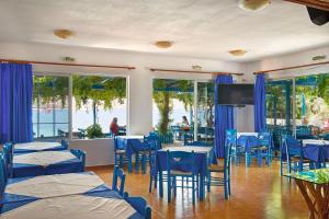 a restaurant with blue tables and chairs and windows at Faros Rooms in Livadia