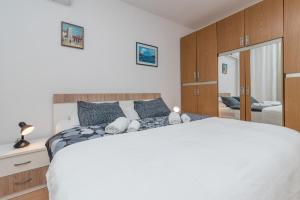 a bedroom with a large white bed and a mirror at Apartments Vojin in Trogir