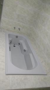 a white bath tub in a tiled bathroom at Hotel Mariluz in Telêmaco Borba