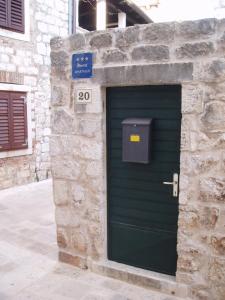 een groene deur in een stenen gebouw met een bord bij Mirina in Stari Grad