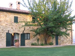 una casa di mattoni con un albero di fronte di Azienda Agraria Montelujano a Gubbio