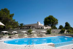 a swimming pool with umbrellas and a resort at Masseria Panareo in Otranto