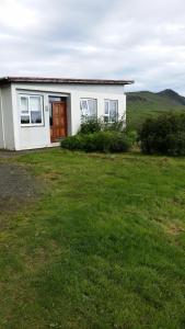 a small white house with a grass yard at Giljur Guesthouse in Vík