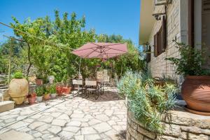 a patio with a pink umbrella and chairs and plants at Villa Kiki Paxos Ozias in Gaios