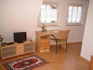 salon z biurkiem, telewizorem i stołem w obiekcie Pension Deimel w mieście Hallenberg
