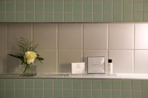 a vase of flowers on a shelf in a bathroom at Hotel an der Stadtmauer in Schorndorf +36 photos