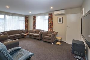 ein Wohnzimmer mit Sofas und einem Flachbild-TV in der Unterkunft Accommodation Fiordland -The Three Bedroom House at 226A Milford Road in Te Anau
