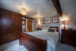 a bedroom with a bed and a dresser with a lamp at The Buttery in Maidstone