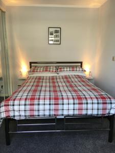 a bedroom with a bed with a red and white plaid blanket at 32a railside in Inverness