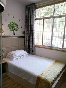 a bedroom with a bed and a window with a tree on the wall at 166 Inn in Fenghuang