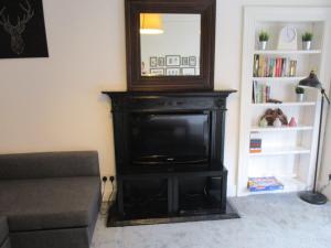 a living room with a television and a mirror at Westend Glasgow Apartment in Glasgow