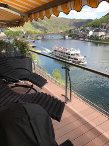a balcony with chairs and a boat on a river at Moselapart in Cochem