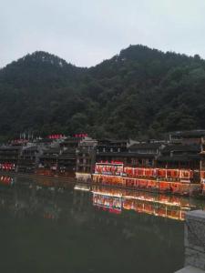 eine Gruppe von Gebäuden neben einem Wasserkörper in der Unterkunft 166 Inn in Fenghuang