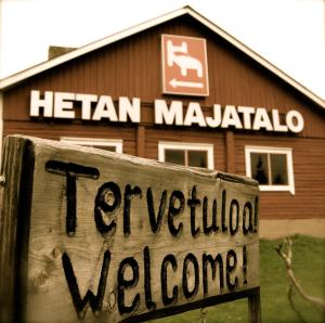 una señal frente a un edificio de madera en Hotel Hetan Majatalo, en Enontekiö