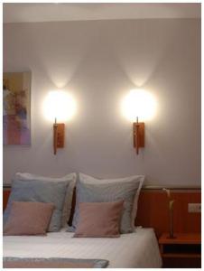 two lights on the wall above a bed with pillows at Hotel South Charleroi Airport in Charleroi