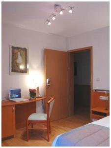 een slaapkamer met een bed en een bureau met een laptop bij Hotel South Charleroi Airport in Charleroi