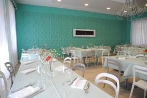 jadalnia z białymi stołami i zieloną ścianą w obiekcie GG8 Hotel & Suite SPA w mieście Gualdo Tadino