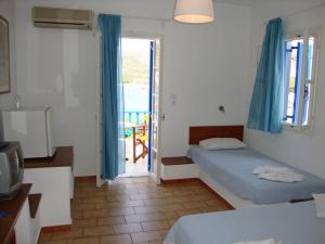 a bedroom with two beds and a door to a balcony at Hotel Minoa in Katapola +17 photos