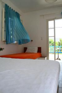 a white bed in a bedroom with a window at Hotel Minoa in Katapola