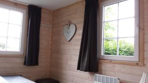 スロースケルケにあるzeeuwse chalet voor 2 personenのベッドルーム1室(窓2つ、壁掛け時計付)