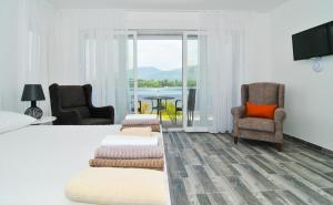 a bedroom with a bed and two chairs and a television at Apartments Edera in Tivat