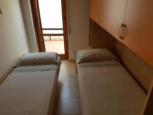 2 Betten in einem kleinen Zimmer mit Fenster in der Unterkunft Residenza Carone in Porto Cesareo