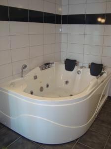 a white bath tub in a tiled bathroom at Thorupgaard Farm Holiday in Stenum