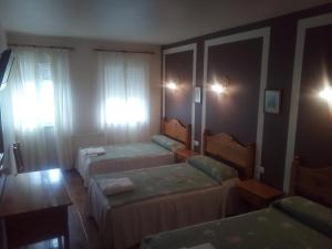Habitación de hotel con 2 camas y mesa en Hotel Restaurante Las Camelias, en Jarrio