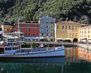 um barco sentado na água em frente aos edifícios em Hotel Europa - Skypool & Panorama em Riva del Garda
