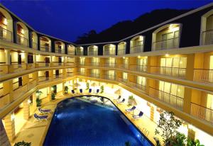 a large building with a swimming pool at night at Kalim Resort in Patong Beach