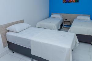 a room with two beds and a blue wall at Pojuca Plaza Hotel in Pojuca
