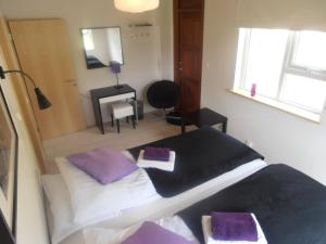 um quarto com uma cama com almofadas roxas e uma secretária em Giljur Guesthouse em Vík