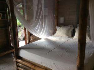 a bedroom with a bed with a mosquito net at Ali-Naïs Location in Deshaies