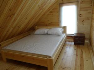 a bed in a room with a wooden wall at Cottages on Polyova in Zgorany