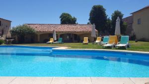 a pool with chairs and umbrellas next to a house at Hospedaria do Convento d'Aguiar- Turismo de Habitacao in Figueira de Castelo Rodrigo