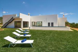 a group of lounge chairs on a lawn in front of a house at Mercedes Country House in Faro